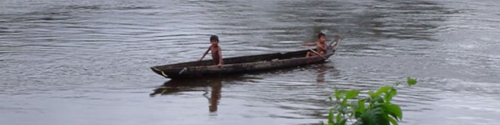 Two boys in a boat along a river in Suriname